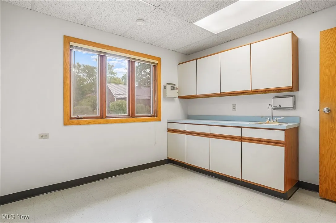 Kitchen with sink, a drop ceiling, and white cabinetry