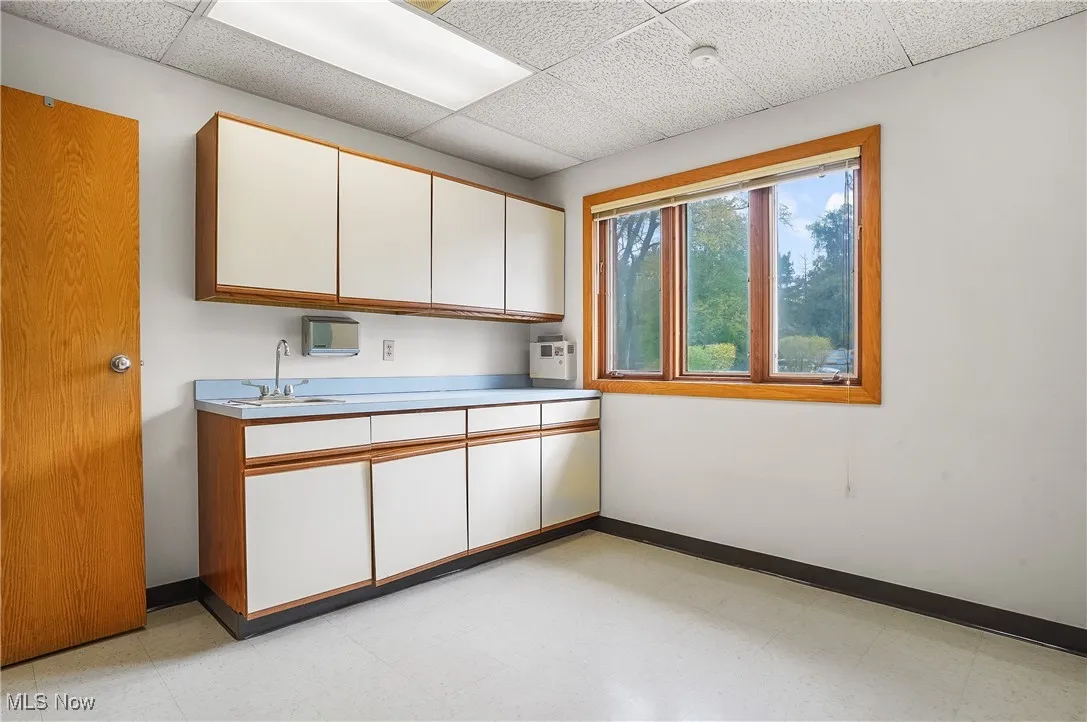 Kitchen featuring sink, white cabinetry, and a paneled ceiling