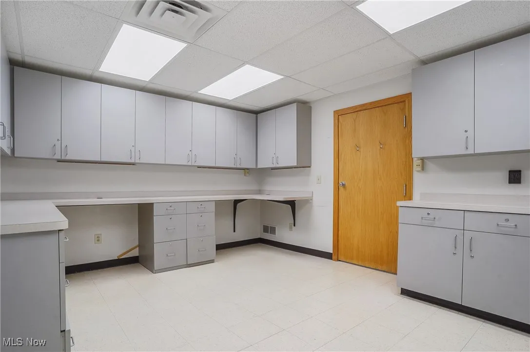 Unfurnished office featuring built in desk and a paneled ceiling