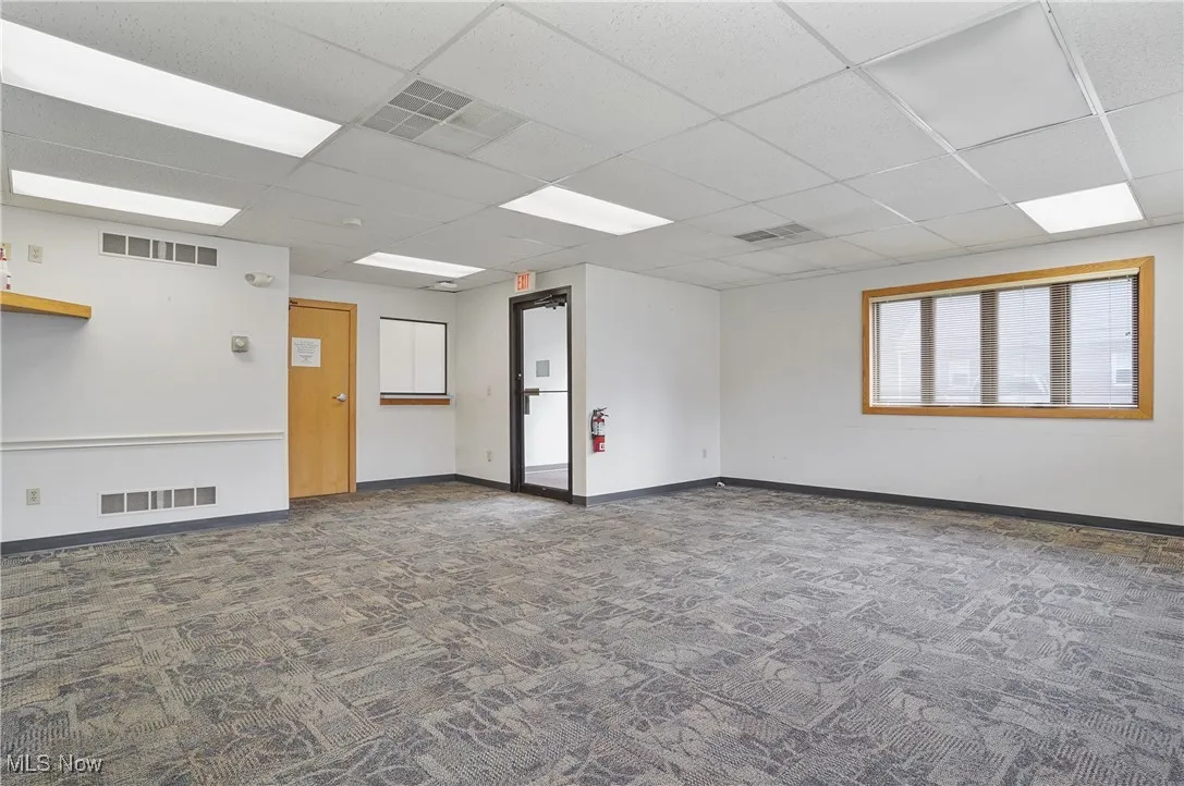 Carpeted spare room featuring a paneled ceiling