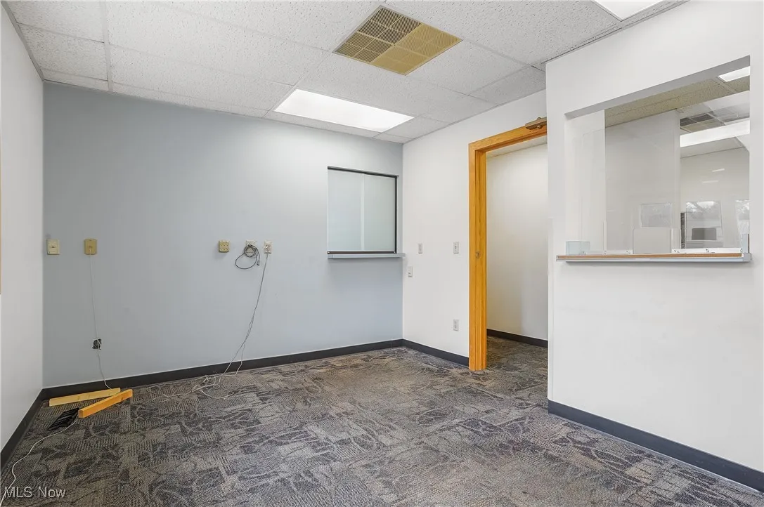Spare room featuring a paneled ceiling and dark carpet