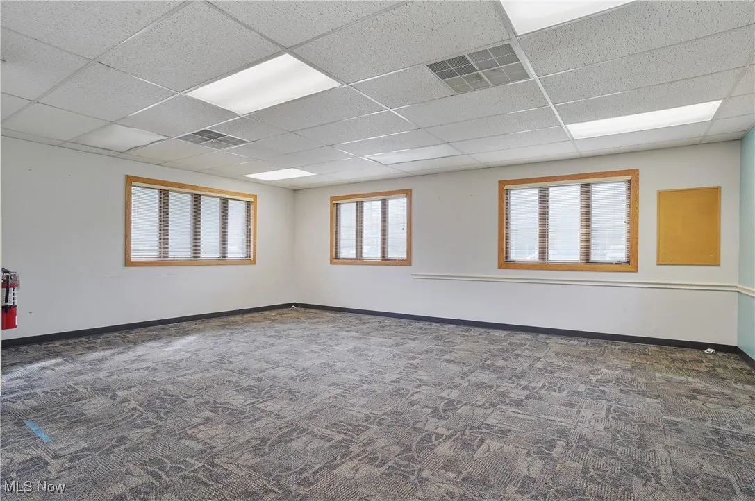 Carpeted empty room featuring a wealth of natural light and a drop ceiling