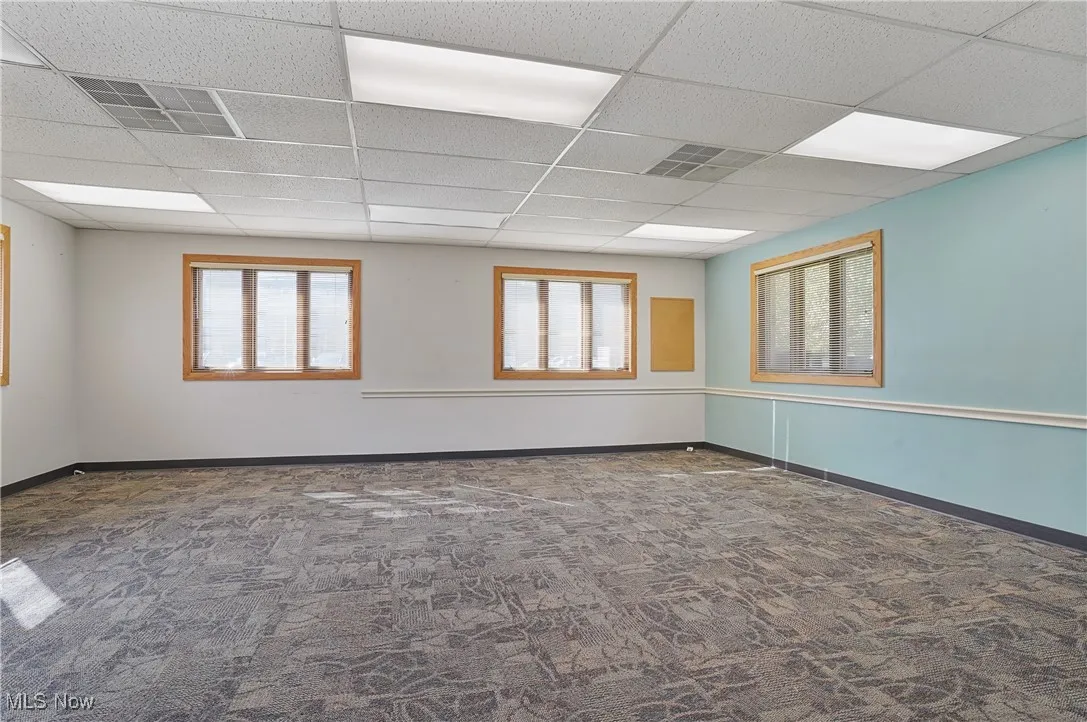 Carpeted empty room featuring a paneled ceiling and a healthy amount of sunlight
