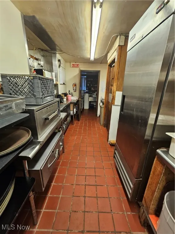 Kitchen with dark tile patterned floors and refrigerator