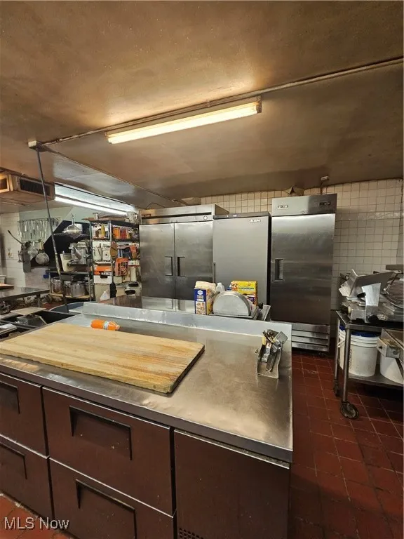 Kitchen featuring refrigerator and stainless steel fridge with ice dispenser