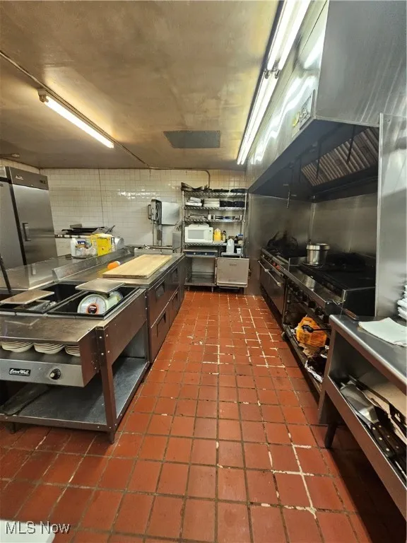 Kitchen featuring dark tile patterned floors and decorative backsplash