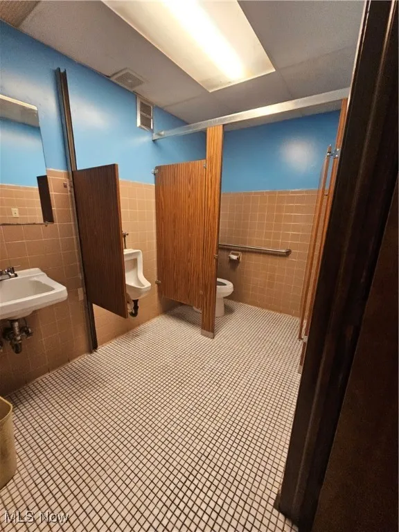 Bathroom with toilet, sink, and tile walls