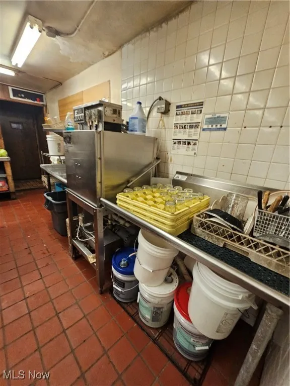 Miscellaneous room with dark tile patterned floors and tile walls