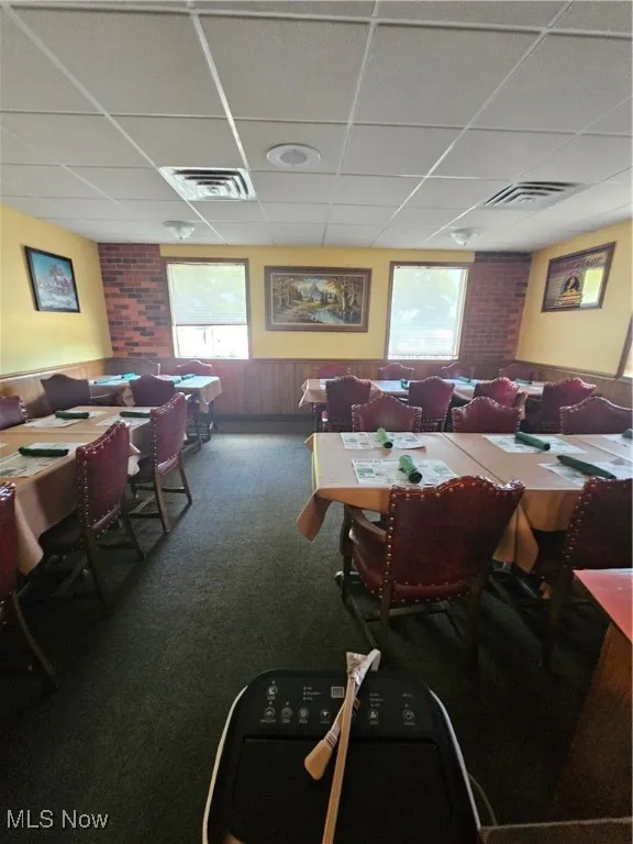 Dining area with a paneled ceiling and carpet
