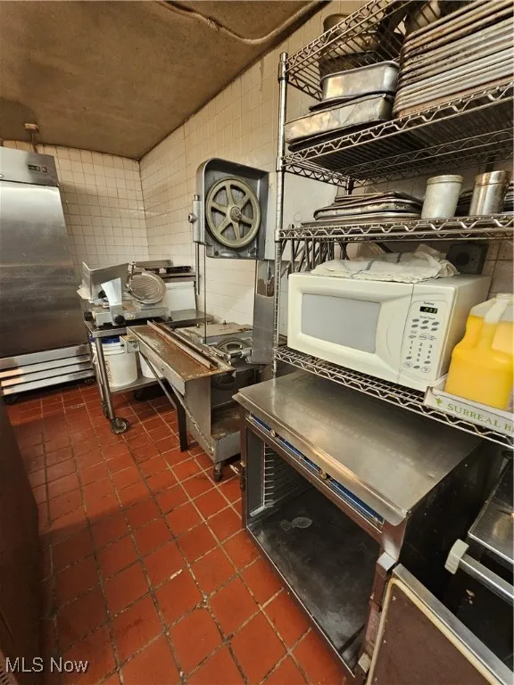 Kitchen featuring dark tile patterned floors and tile walls