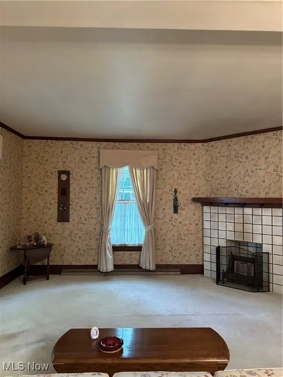  living room with ornamental molding, a tile fireplace, and carpet floors