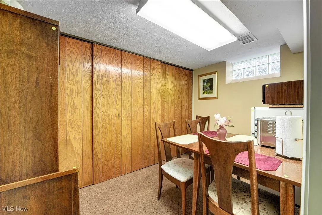 Carpeted lunch room featuring a textured ceiling and wooden walls