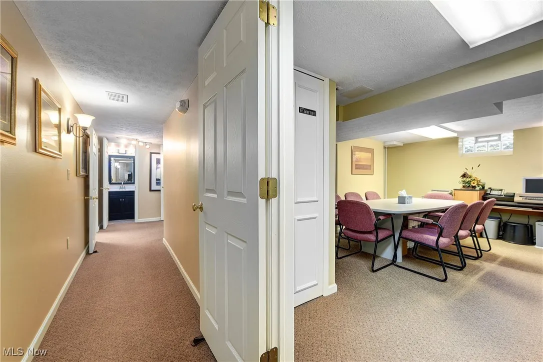 Corridor featuring a textured ceiling and light colored carpet