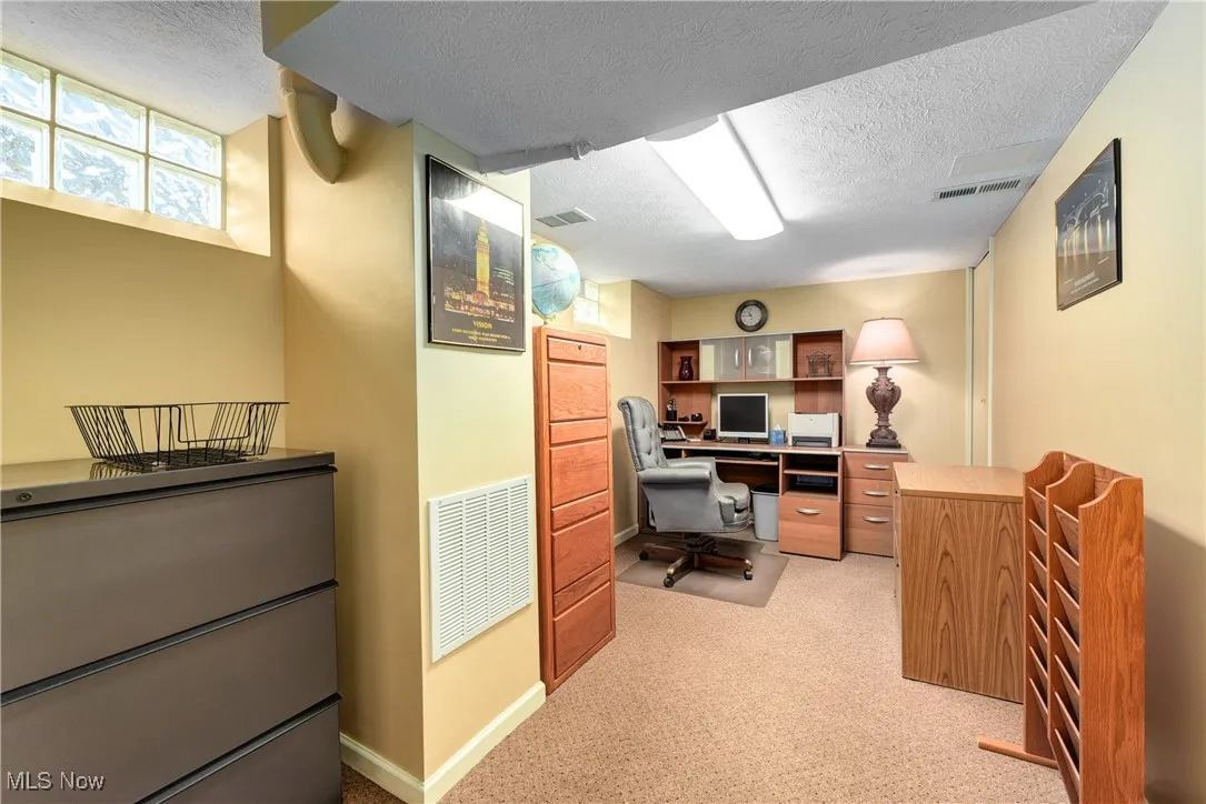 Office featuring a textured ceiling and light colored carpet