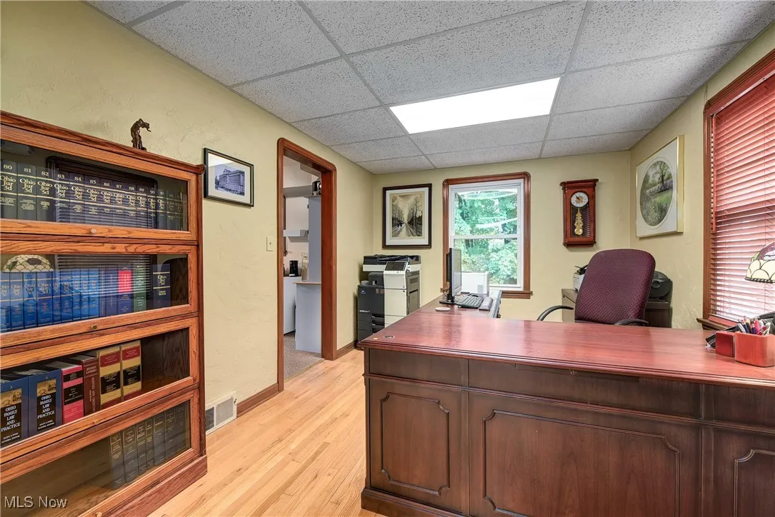 Home office featuring light hardwood / wood-style floors and a paneled ceiling
