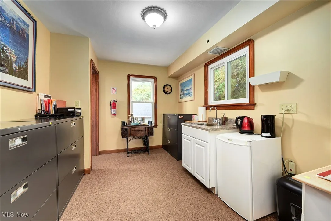 Kitchenette featuring white cabinetry, sink, white refrigerator, and light colored carpet