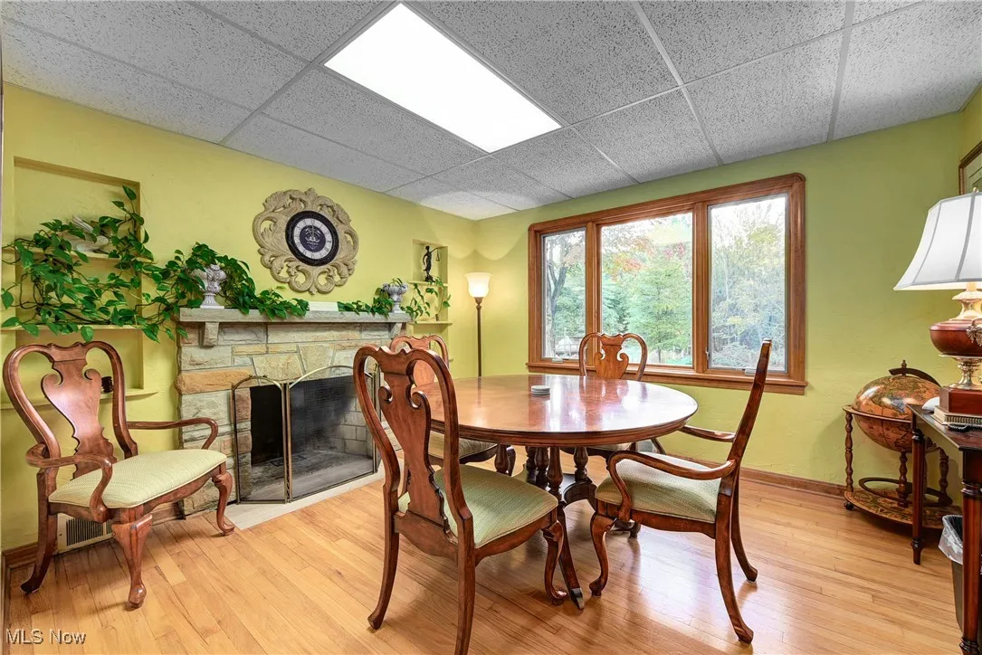Conference Room/ Office Up with a drop ceiling, a stone fireplace, and light wood-type flooring