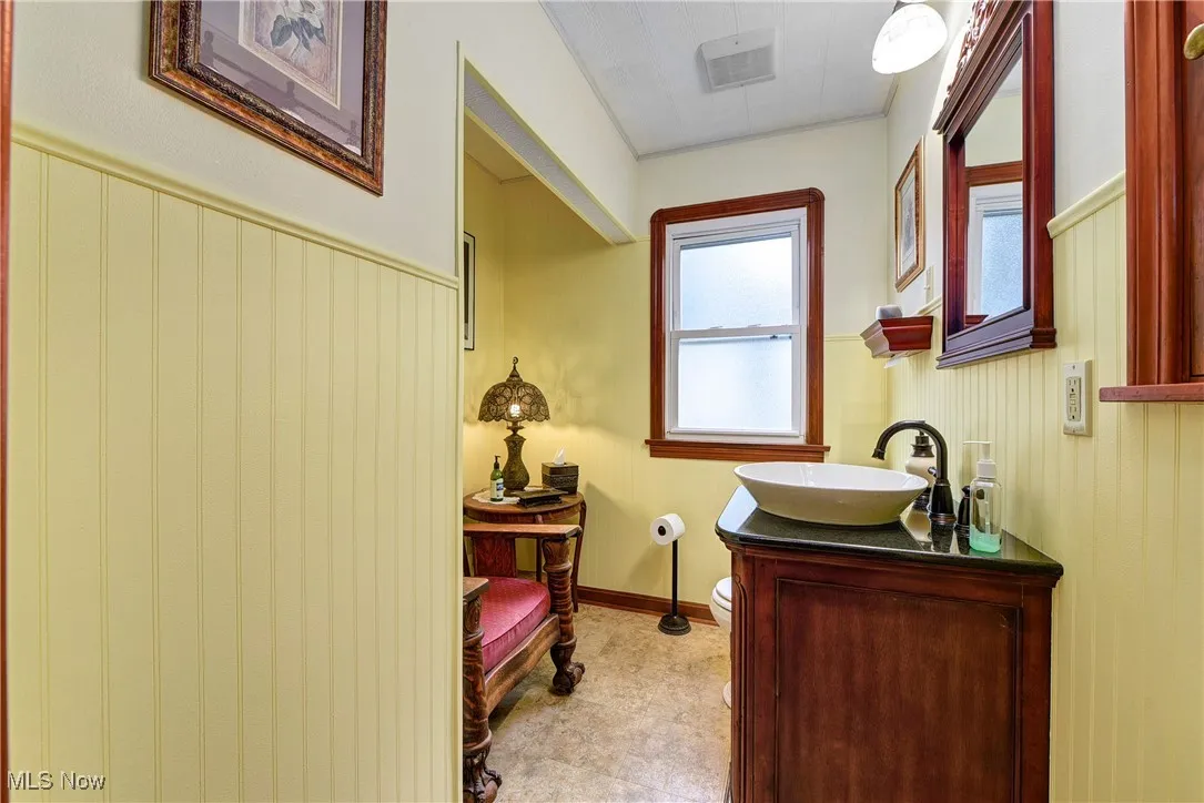 Bathroom featuring toilet, wood walls, and vanity