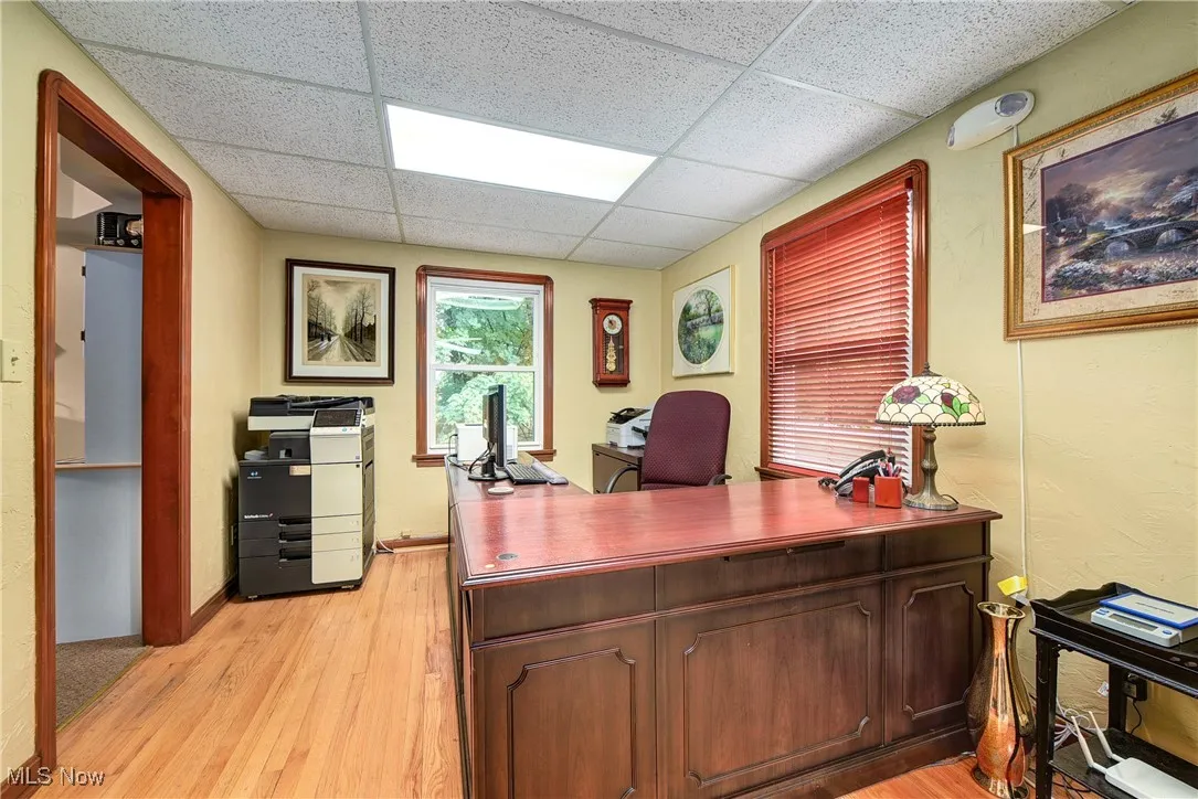 Office area with a drop ceiling and light hardwood / wood-style flooring