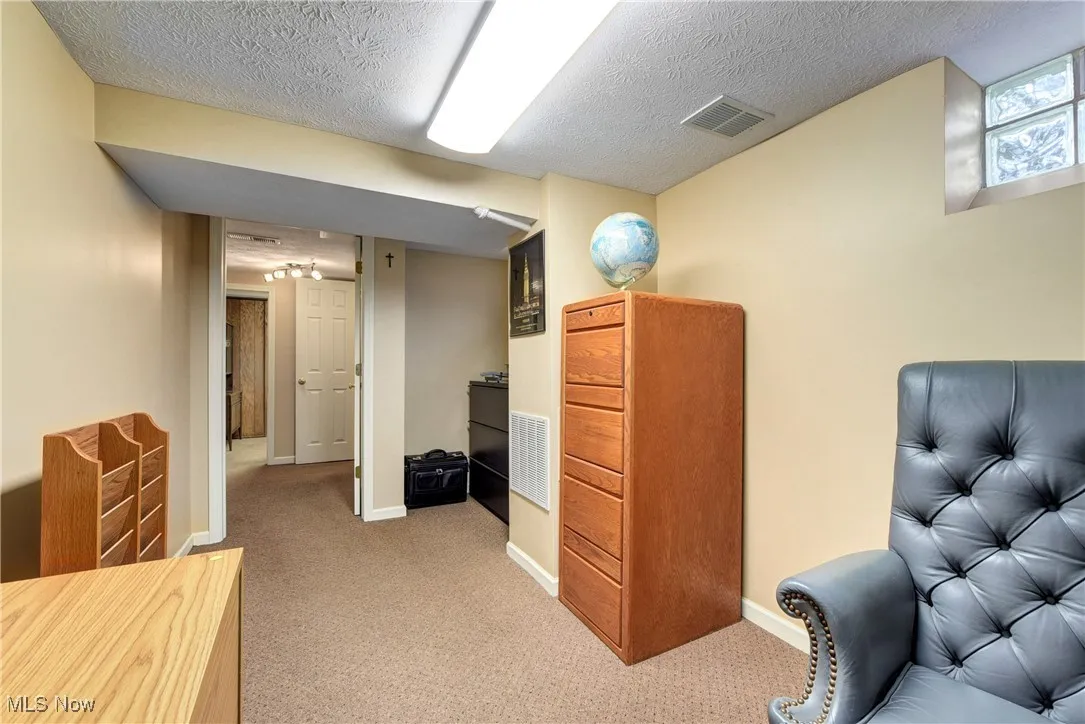 Living area featuring light carpet and a textured ceiling