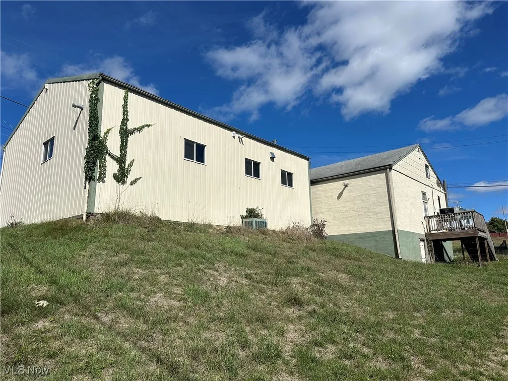 View of property exterior featuring a wooden deck and a yard