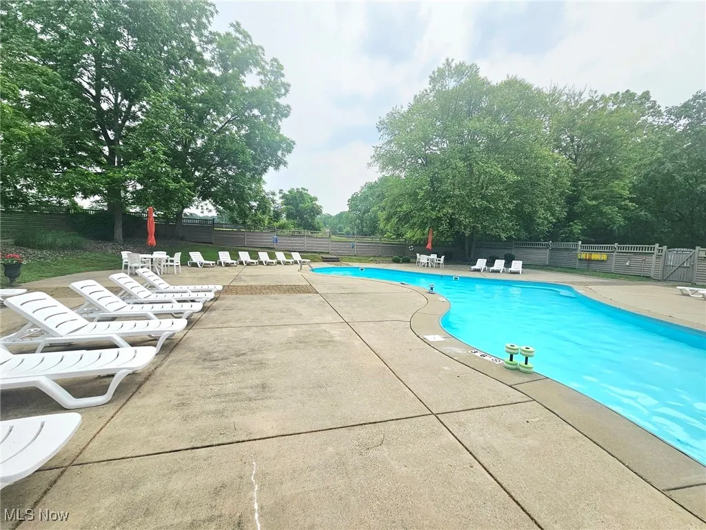 Community pool featuring a patio area and view of scattered trees