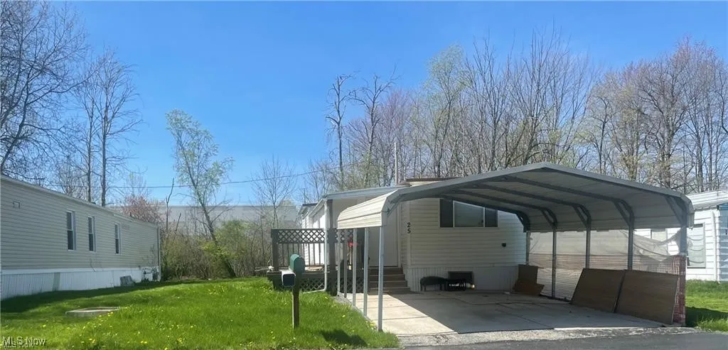 View of parking / parking lot with a yard and a carport