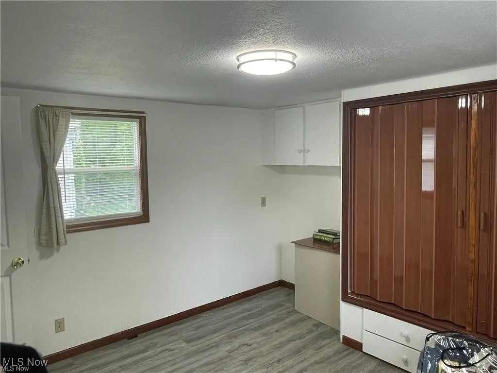 Laundry room featuring a textured ceiling and light hardwood / wood-style floors