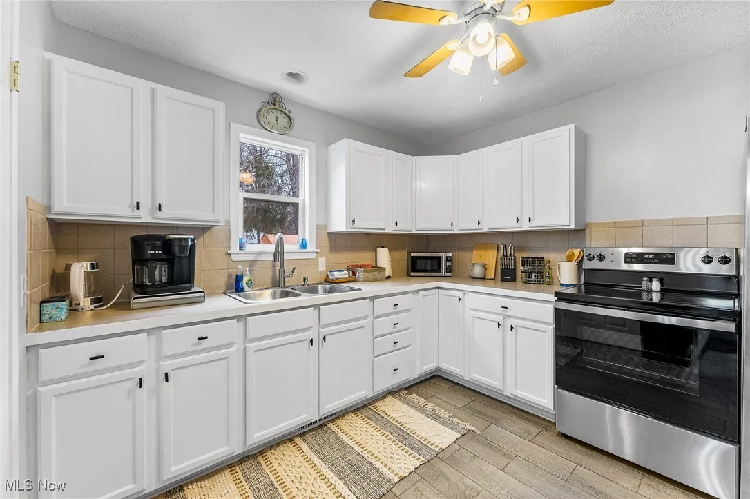 Kitchen featuring white cabinets, tasteful backsplash, stainless steel appliances, and sink