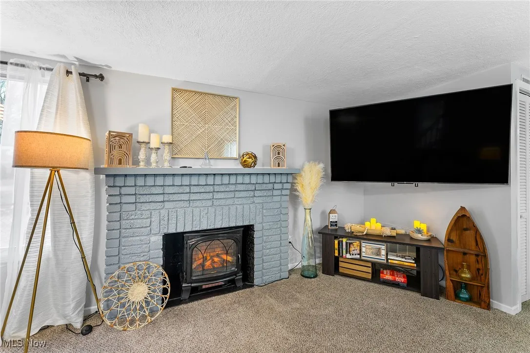 Carpeted living room with a textured ceiling and a fireplace