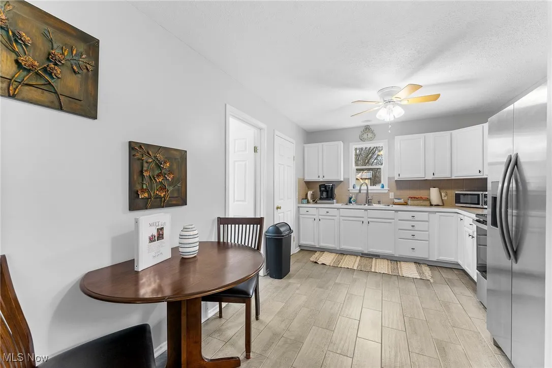 Kitchen with ceiling fan, appliances with stainless steel finishes, a textured ceiling, white cabinetry, and sink