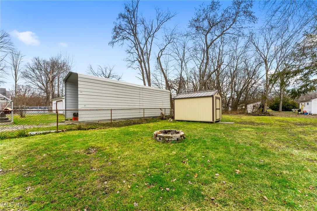 View of yard with an outdoor fire pit and a storage unit