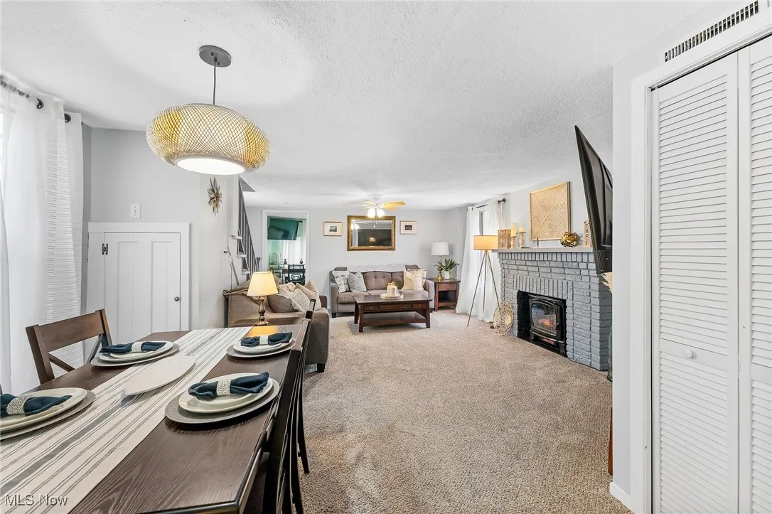 Dining room with carpet floors, a healthy amount of sunlight, a textured ceiling, and a brick fireplace