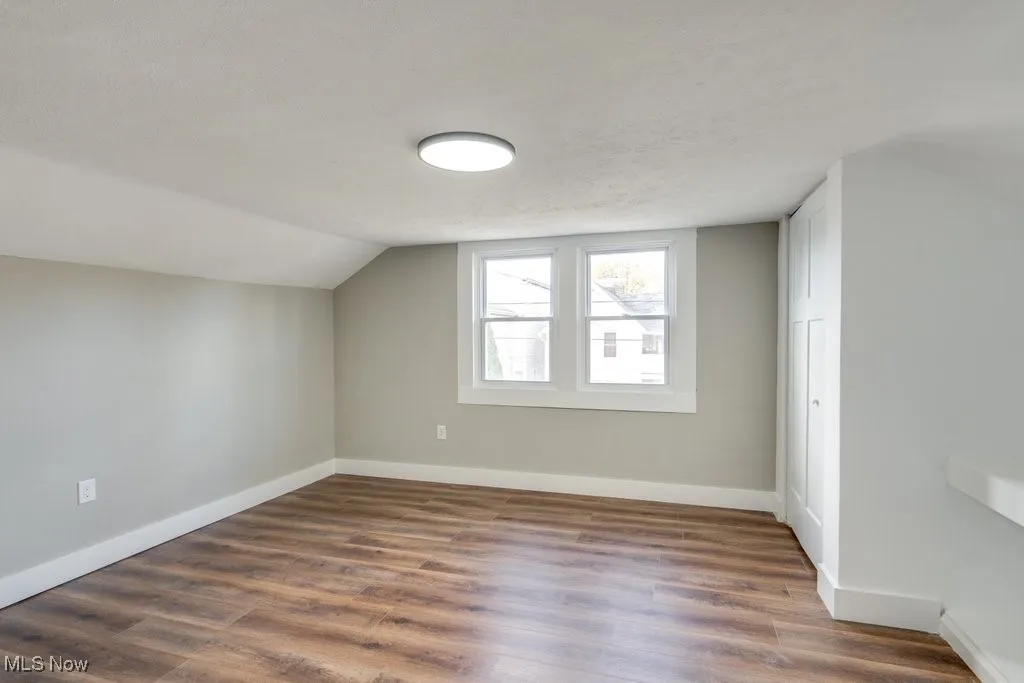 Bonus room featuring lofted ceiling, a textured ceiling, and dark hardwood / wood-style flooring