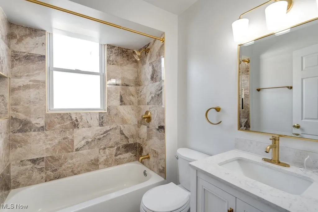 Full bathroom with tiled shower / bath, vanity, and toilet