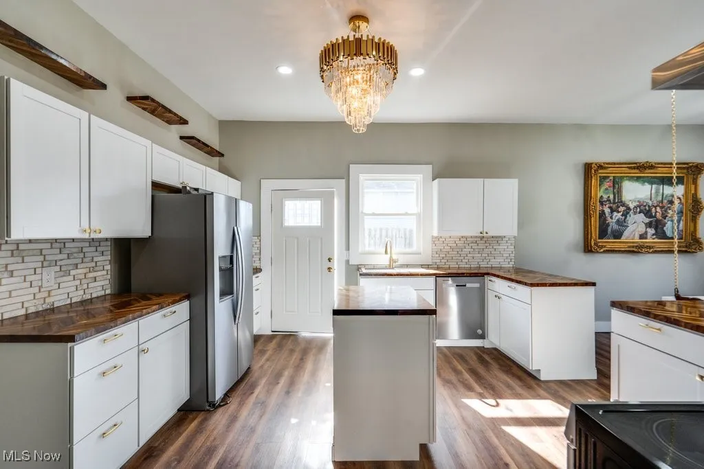Kitchen featuring appliances with stainless steel finishes, white cabinets, a center island, and dark hardwood / wood-style floors