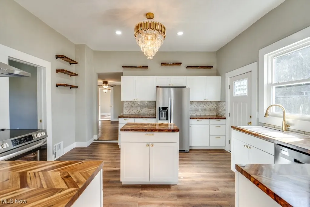 Kitchen featuring butcher block countertops, appliances with stainless steel finishes, light hardwood / wood-style flooring, and white cabinets
