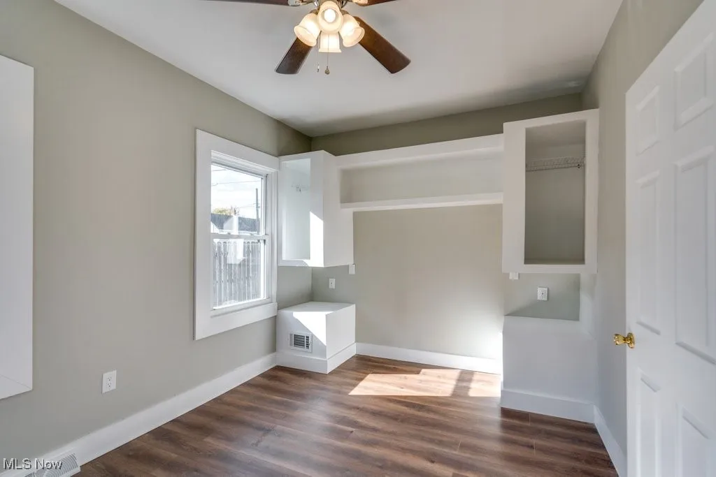 Unfurnished bedroom with a closet, dark hardwood / wood-style floors, and ceiling fan