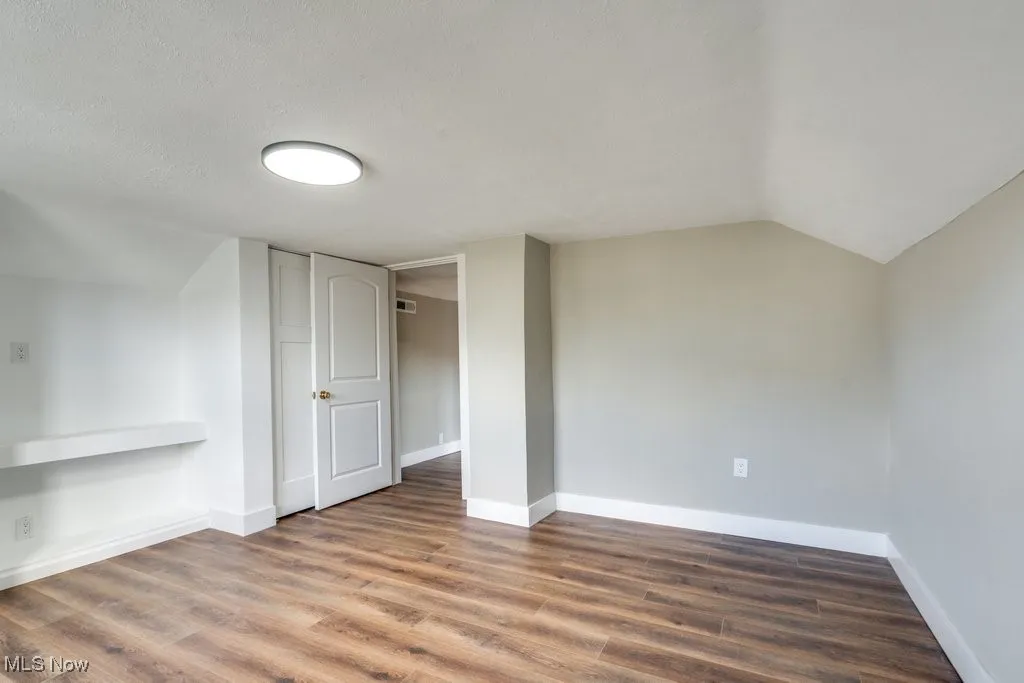 Additional living space with lofted ceiling, a textured ceiling, and dark hardwood / wood-style flooring