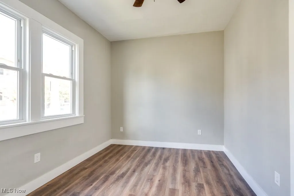 Spare room with dark hardwood / wood-style floors, a healthy amount of sunlight, and ceiling fan