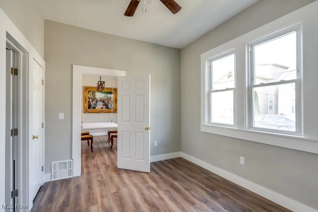Unfurnished bedroom with multiple windows, wood-type flooring, and ceiling fan