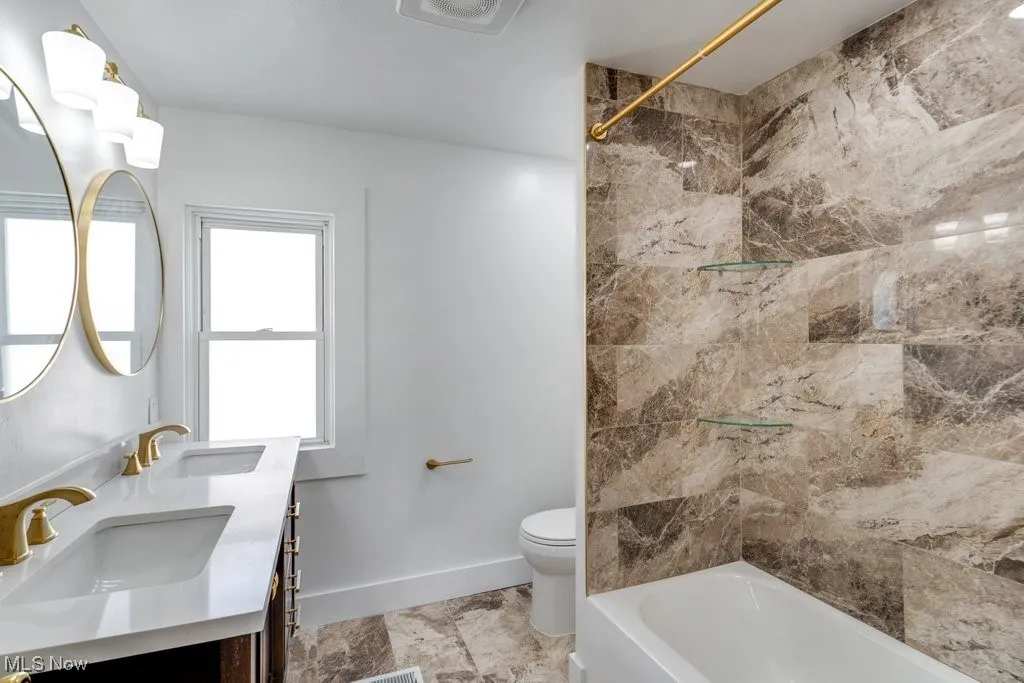 Full bathroom with toilet, tiled shower / bath combo, and vanity