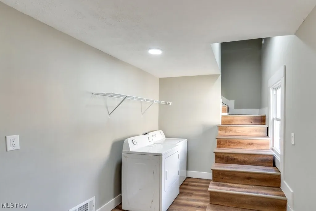 Clothes washing area featuring separate washer and dryer and hardwood / wood-style floors
