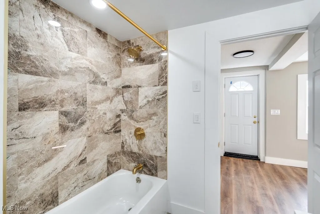 Bathroom with tiled shower / bath combo and hardwood / wood-style flooring