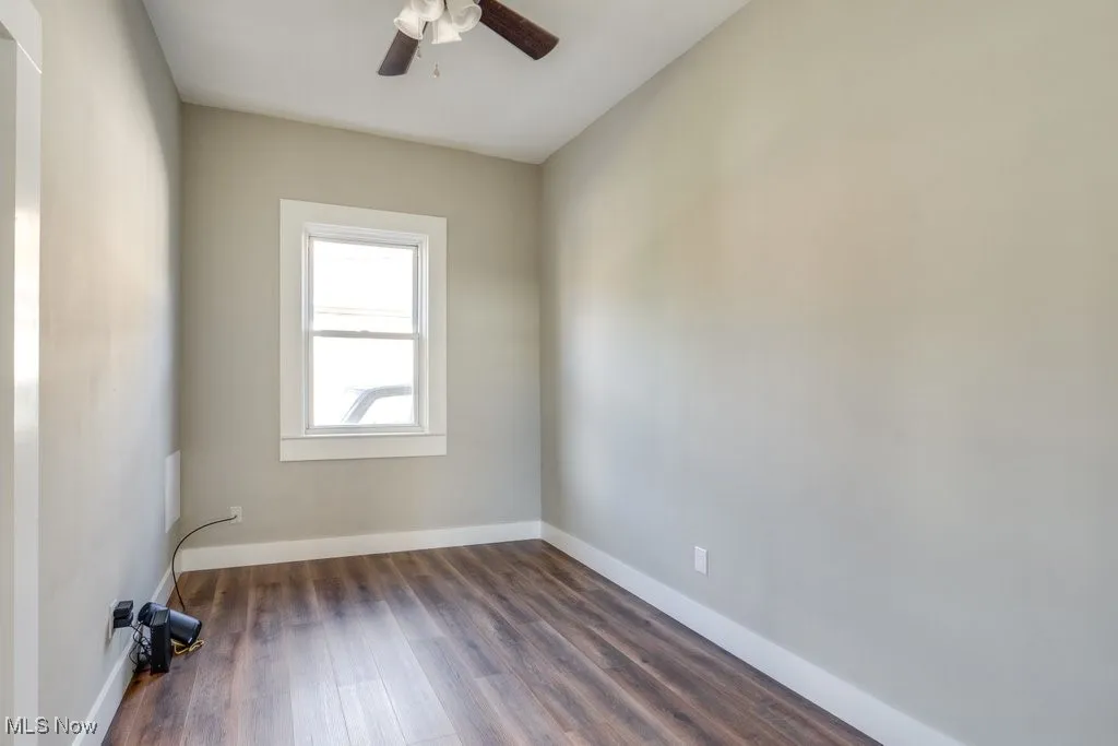 Spare room featuring dark wood-type flooring and ceiling fan