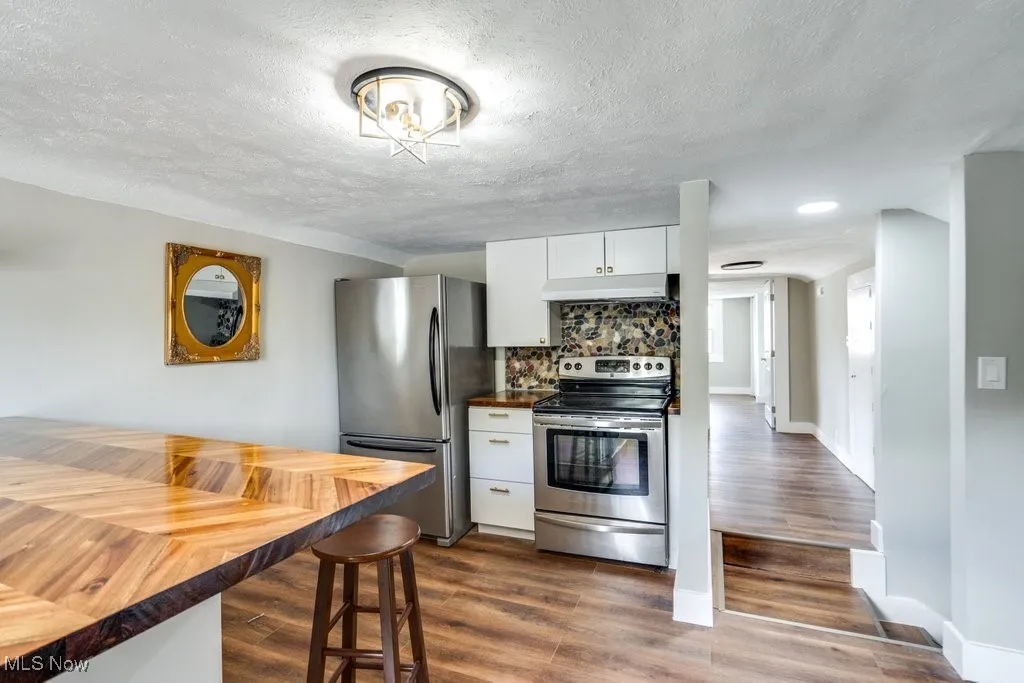 Kitchen featuring white cabinetry, appliances with stainless steel finishes, a textured ceiling, and dark hardwood / wood-style floors