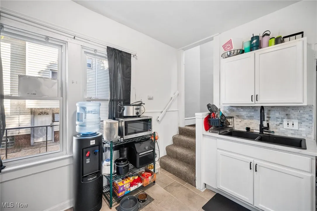 Kitchen featuring sink, white cabinets, decorative backsplash, and light tile patterned floors