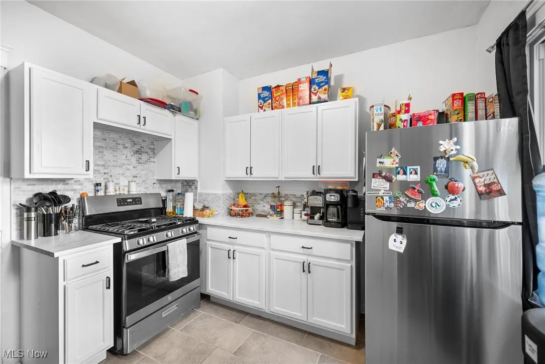 Kitchen featuring backsplash, stainless steel appliances, and white cabinets