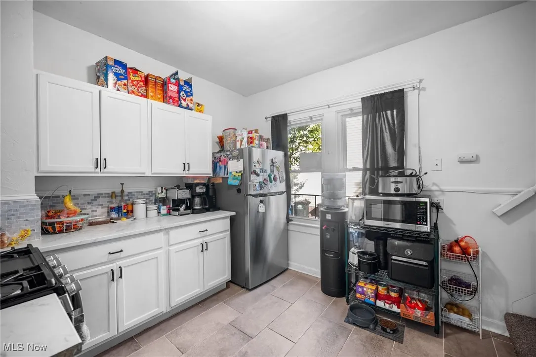 Kitchen featuring appliances with stainless steel finishes, white cabinetry, tasteful backsplash, and light tile patterned floors