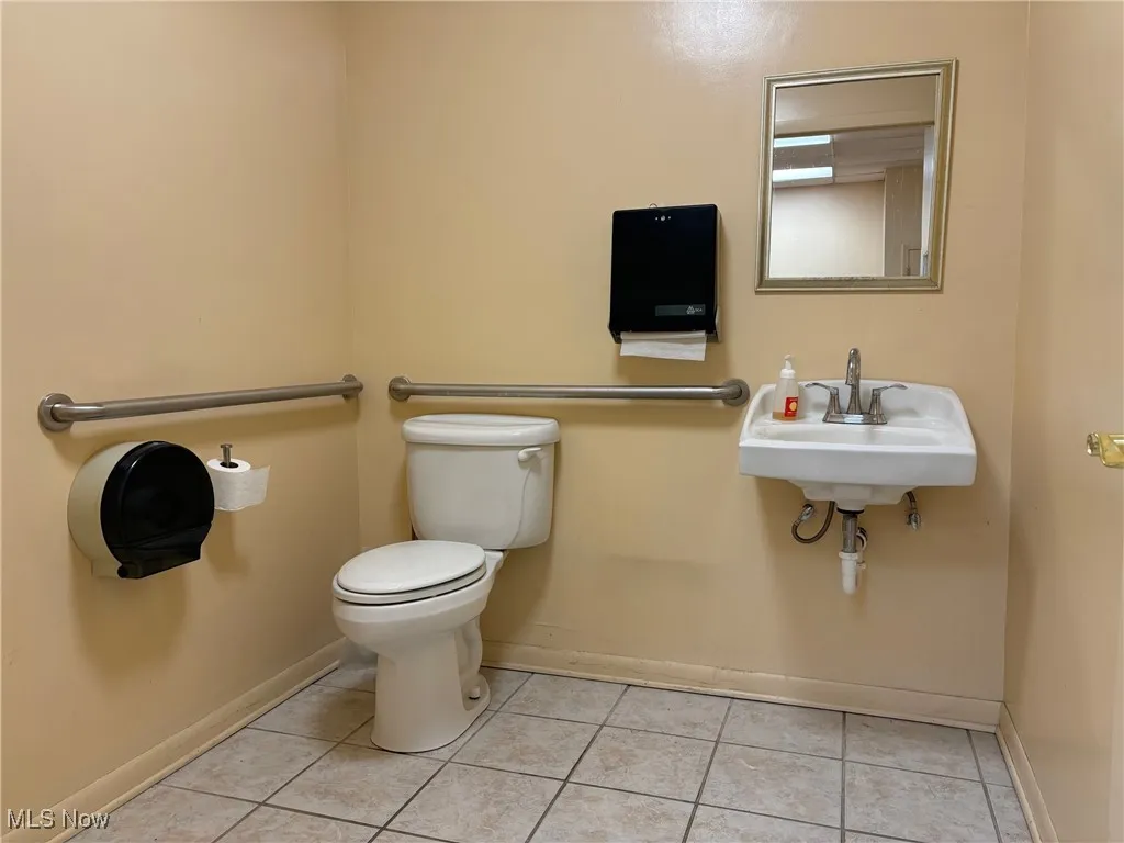 First floor bathroom with toilet, sink, and tile patterned flooring